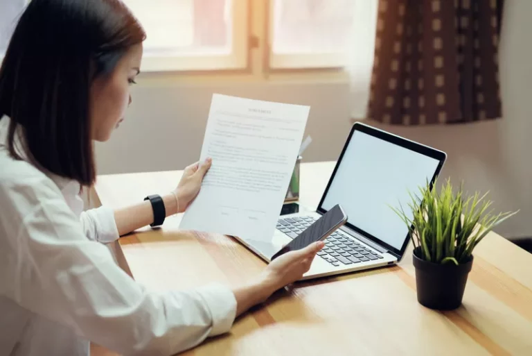 Một người phụ nữ trẻ đang làm việc tại nhà hoặc văn phòng, đọc tài liệu hợp đồng kinh doanh quan trọng